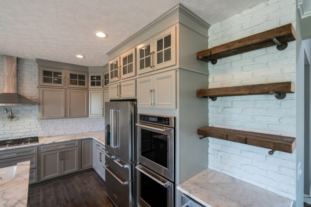 Warm wooden floating shelves in a farmhouse kitchen, displaying cookbooks and wooden bowls.