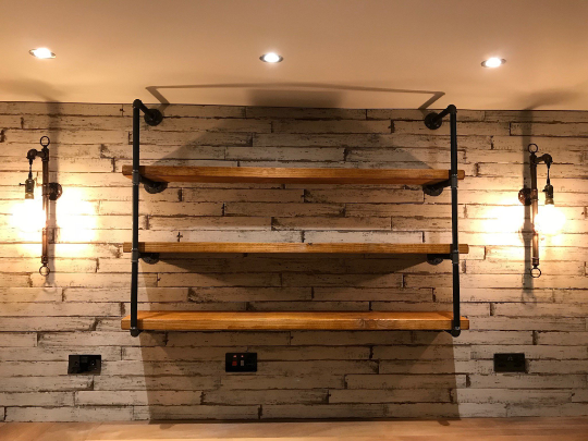 Industrial-style floating shelves with metal brackets and reclaimed wood in a rustic kitchen.

