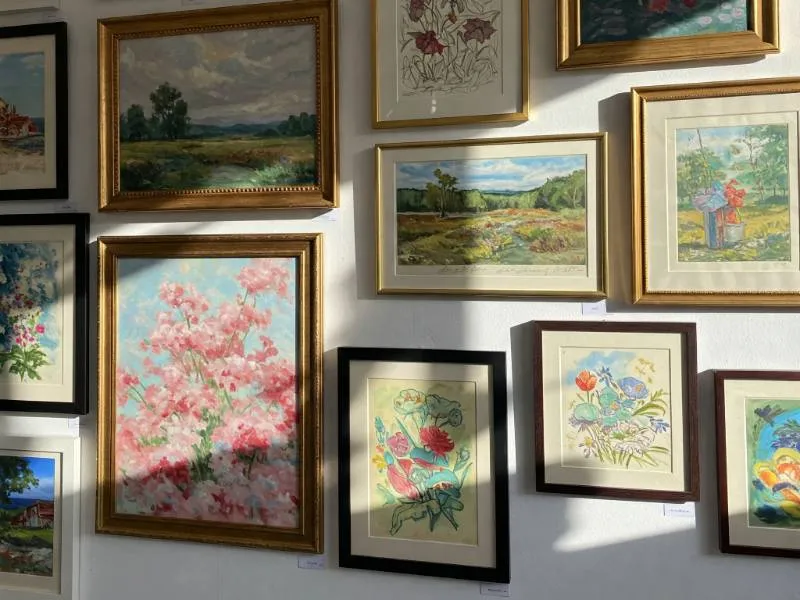 Eclectic collection of framed paintings, sketches, and prints displayed on a neutral-toned wall