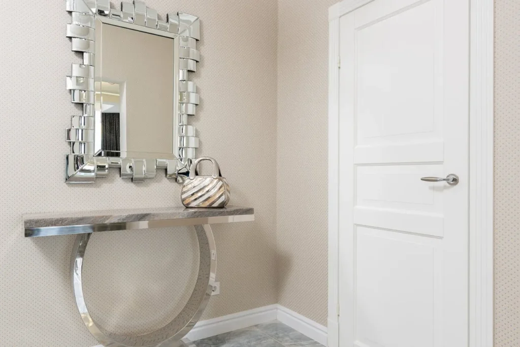 Console Table with Statement Mirror: A console table topped with an ornate gold mirror and classic, elegant decor.